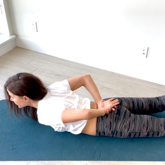 girl on her stomach with hands behind her back doing back exercises