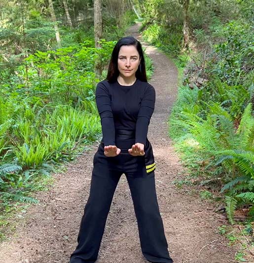 Woman standing on the path in the lush green woods demonstrating a double gum sao
